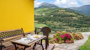 A yellow building with a patio table, a bench, and a chair.