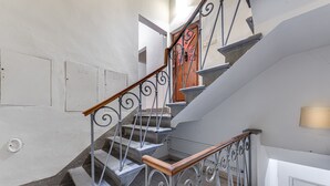A staircase with metal railings and wooden handrails, leading to a door with a red sign.