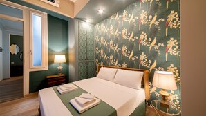 A hotel room with a bed, a nightstand, a lamp, and a wall with a floral pattern.