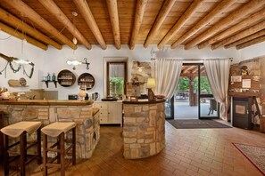 Une cuisine rustique avec des comptoirs en pierre, des tabourets en bois et un bar en pierre.