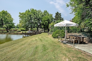 Un jardin bien entretenu, agrémenté d’un étang, de tables de pique-nique et d’un grand parasol.