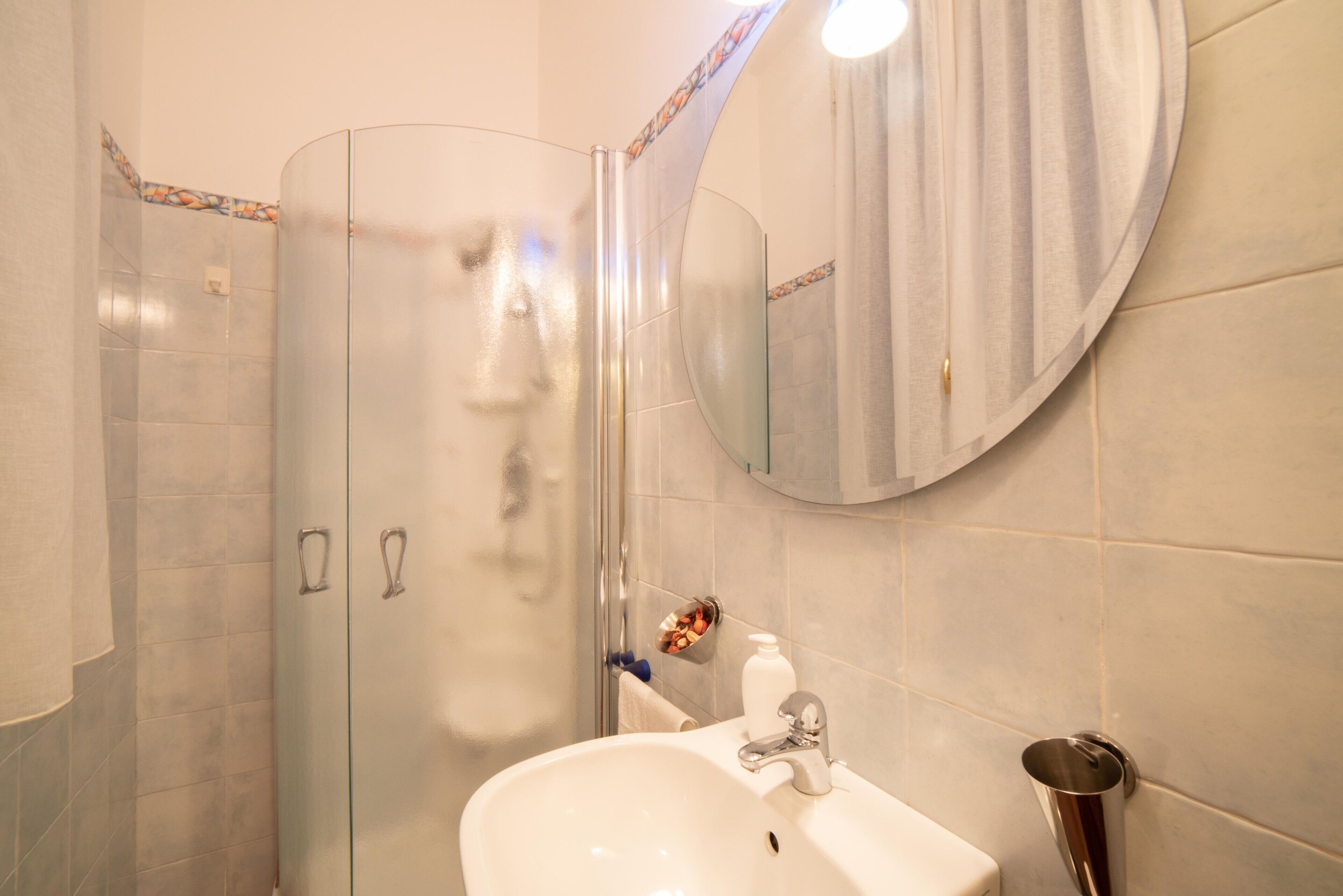 A bathroom with a glass shower enclosure, a sink with a mirror, and a toilet.