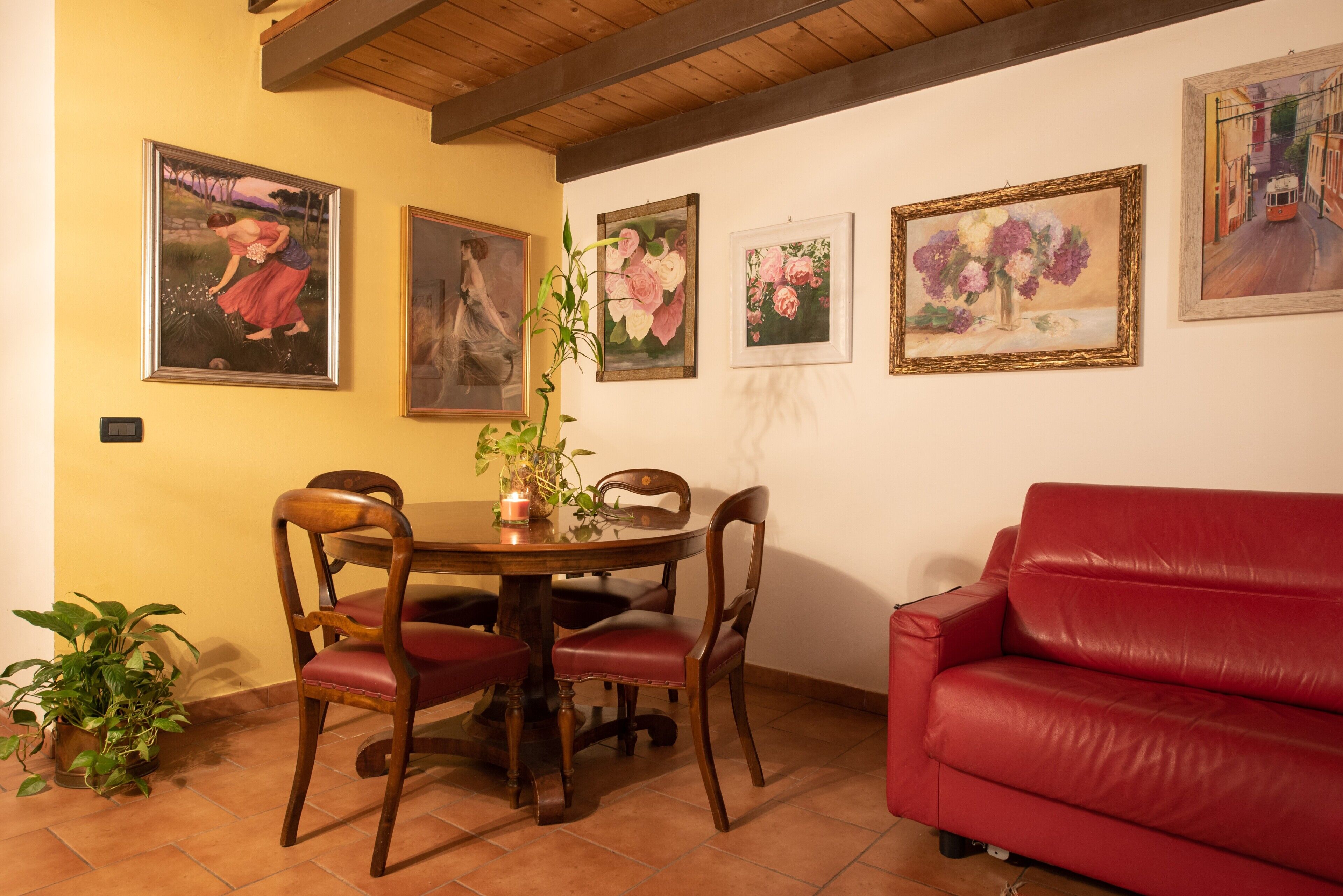 A dining area with a wooden table, chairs, and a red sofa.