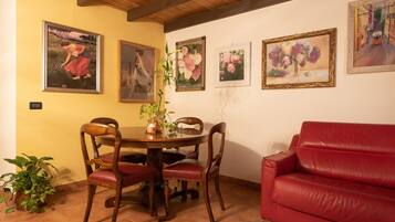 A dining area with a wooden table, chairs, and a red sofa.