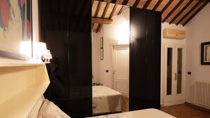 Een slaapkamer met een bed, nachtkastje, spiegel en garderobe.