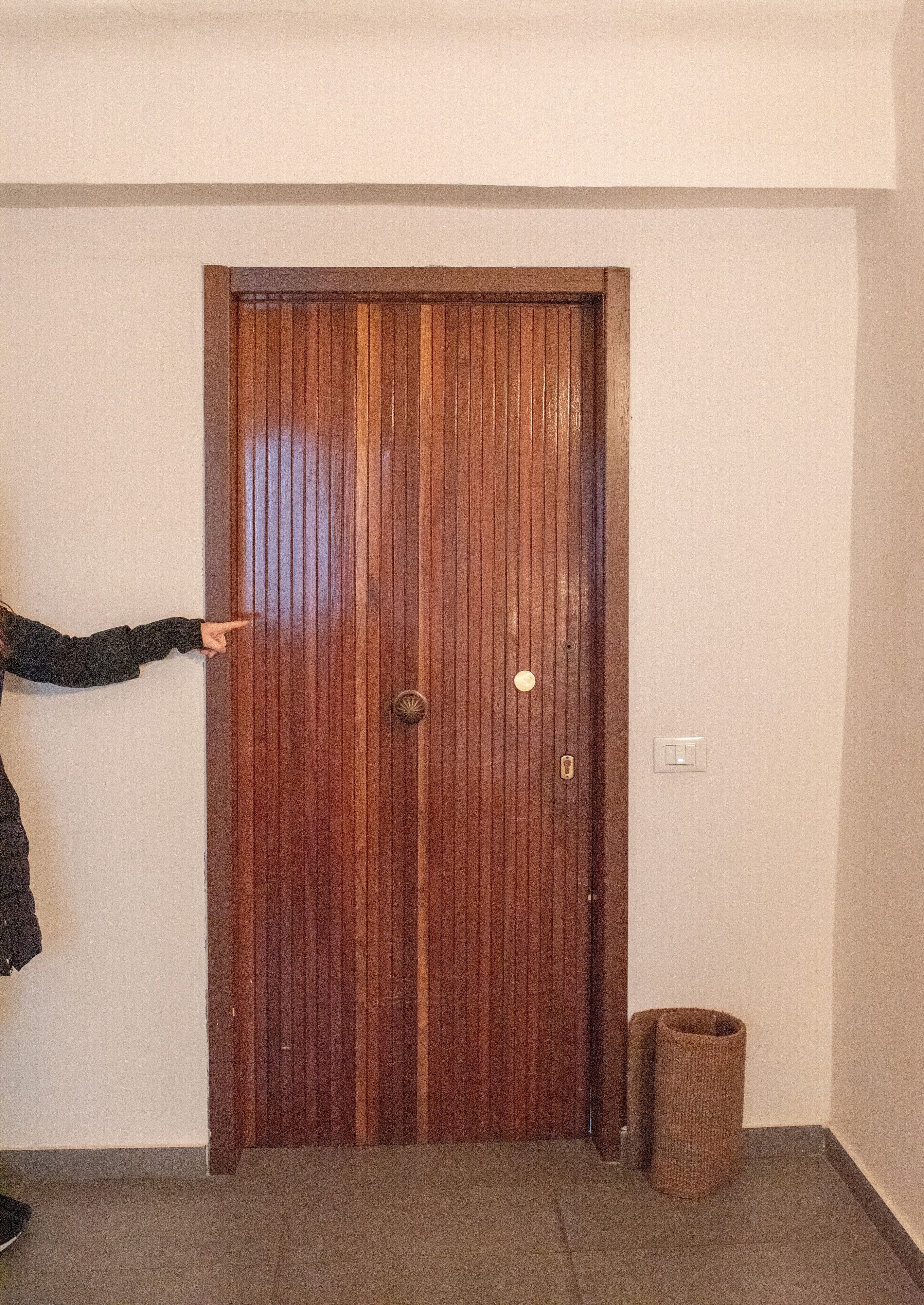 Una puerta de madera con un picaporte, una cerradura y un interruptor de luz en la pared.