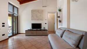 Een woonkamer met een bank, televisie, kasten en een behangen muur.