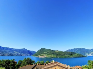 A view of a lake with mountains in the background and a building with a tiled roof in the foreground.