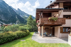 A mountain lodge with a balcony, outdoor seating, and a view of the surrounding forest and mountains. - Apartment 'La Bévéria 5' with Private Terrace and Shared Garden (Pralognan-la-Vanoise)