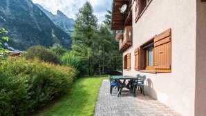 Ein Gebäude mit einer gepflasterten Terrasse, einem Tisch mit Stühlen und Blick auf Berge.
