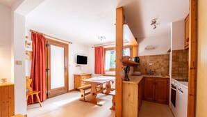 Eine Küche mit Holzausstattung, einem Esstisch und einem eingebauten Backofen.