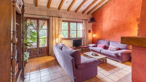 A living room with a sofa, a television, and a coffee table. - Dalt La Figuera Country House — Guadarrama, Mountain Views, Pool & Wi-Fi (La Higuera)