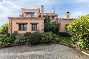 A two-story house with a stone facade, a chimney, and a gravel driveway.