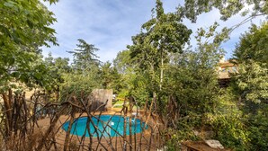 A pool surrounded by trees and a stone wall. - Dalt La Figuera Country House — Guadarrama, Mountain Views, Pool & Wi-Fi (La Higuera)