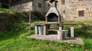Ein Steinhaus mit traditionellem Steinofen, einer Treppe und einer rustikalen Außenanlage.