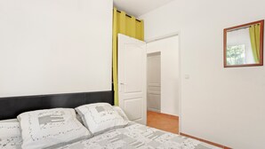 A bedroom with a bed, a door, a mirror, and a view into another room. - Apartment 'Bel 4p St-Maxime' with Private Terrace, Garden, and Wi-Fi (Sainte-Maxime)