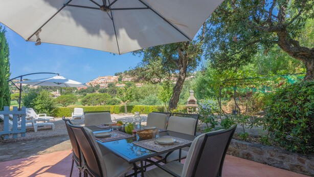 An outdoor patio with a table and chairs, surrounded by greenery and a view of a hillside. - Apartment 'Bel 4p St-Maxime' with Private Terrace, Garden, and Wi-Fi (Sainte-Maxime)