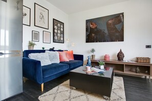 Una sala de estar moderna con un sofá azul, una mesa de centro y obras de arte en las paredes.
