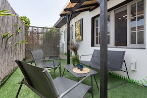 Une terrasse avec des sièges d’extérieur, un vase décoratif et une statue de Bouddha.