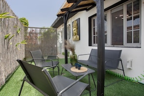 A patio with two chairs, a table, and a Buddha statue.