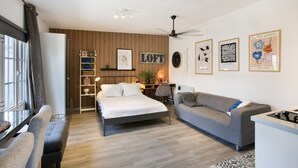 Un dormitorio moderno con cama, sofá, escritorio y ventilador de techo.