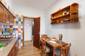 Un coin repas avec une table en bois, des chaises et une étagère au-dessus.
