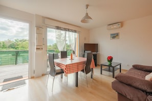 Un coin repas avec une table et des chaises, un canapé, un téléviseur et un balcon avec vue.