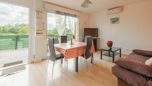 Een zithoek met een tafel en stoelen, een bank, een bijzettafeltje met een vaas en een televisie.