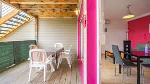 Techo de madera, una escalera, un comedor con sillas y una mesa, y una pared de color rosa brillante.