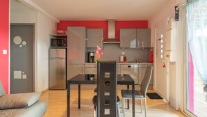Cocina compacta con electrodomésticos modernos, zona de comedor con mesa y sillas, y sofá en la sala.