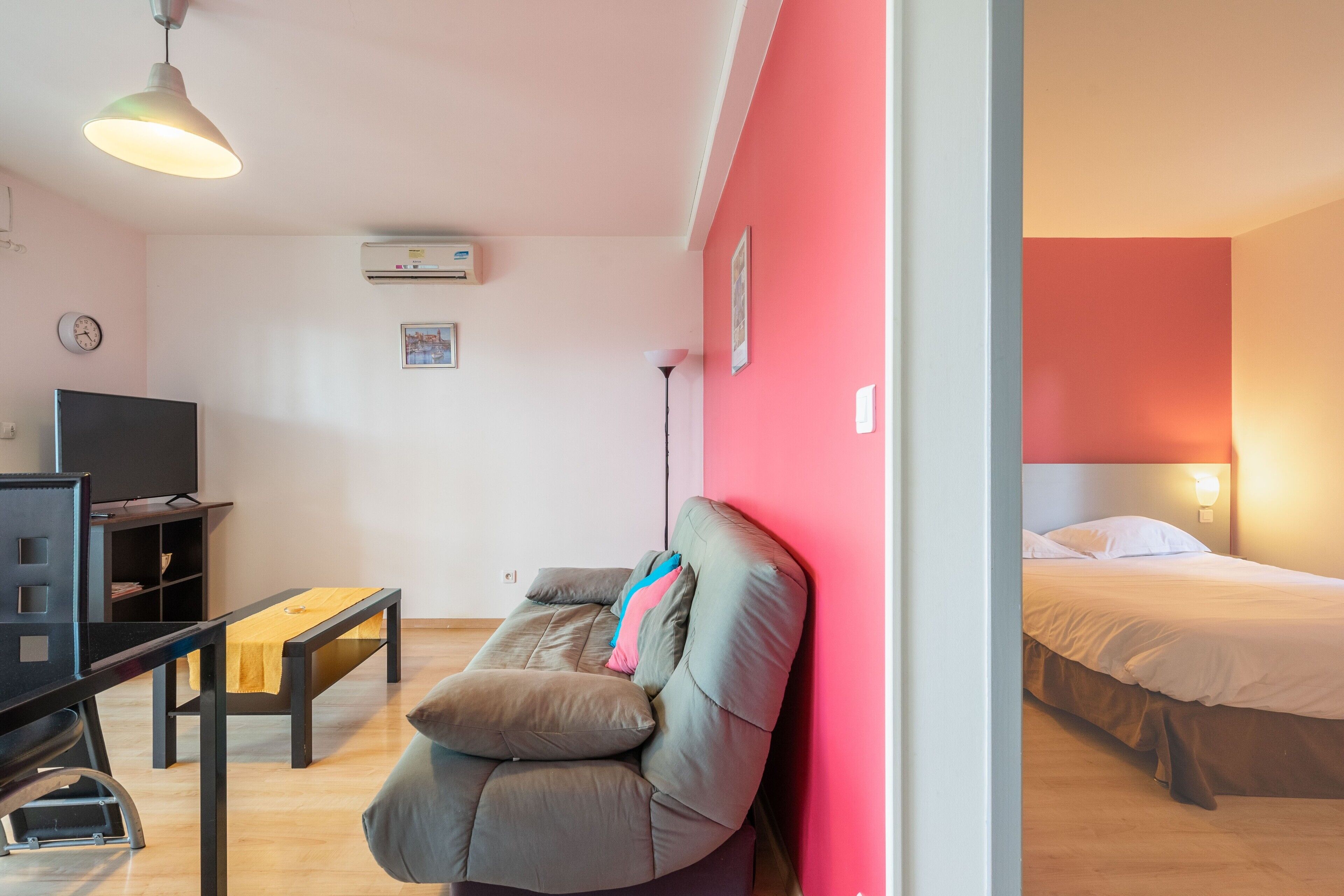 A modern room with a sofa, a TV, a desk, and a bed.