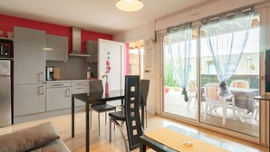 Una cocina moderna con armarios grises, un comedor con mesa y sillas, y un vidrio corredero que da a un patio exterior.