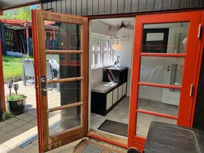 A wooden-framed glass door leading to a kitchen with a black countertop and white cabinets. - Charming and cozy house near Høve beach (Asnæs)