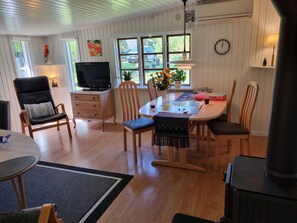 Uma sala de estar aconchegante com uma mesa de jantar, cadeiras, uma televisão e uma lareira.