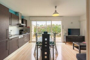 Una cucina moderna con zona pranzo, TV e un'ampia porta scorrevole in vetro che dà su un patio esterno.