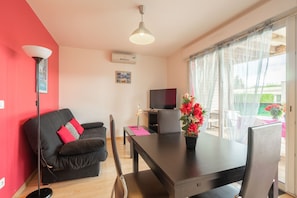 A living room with a black sofa, a dining table, and a TV.