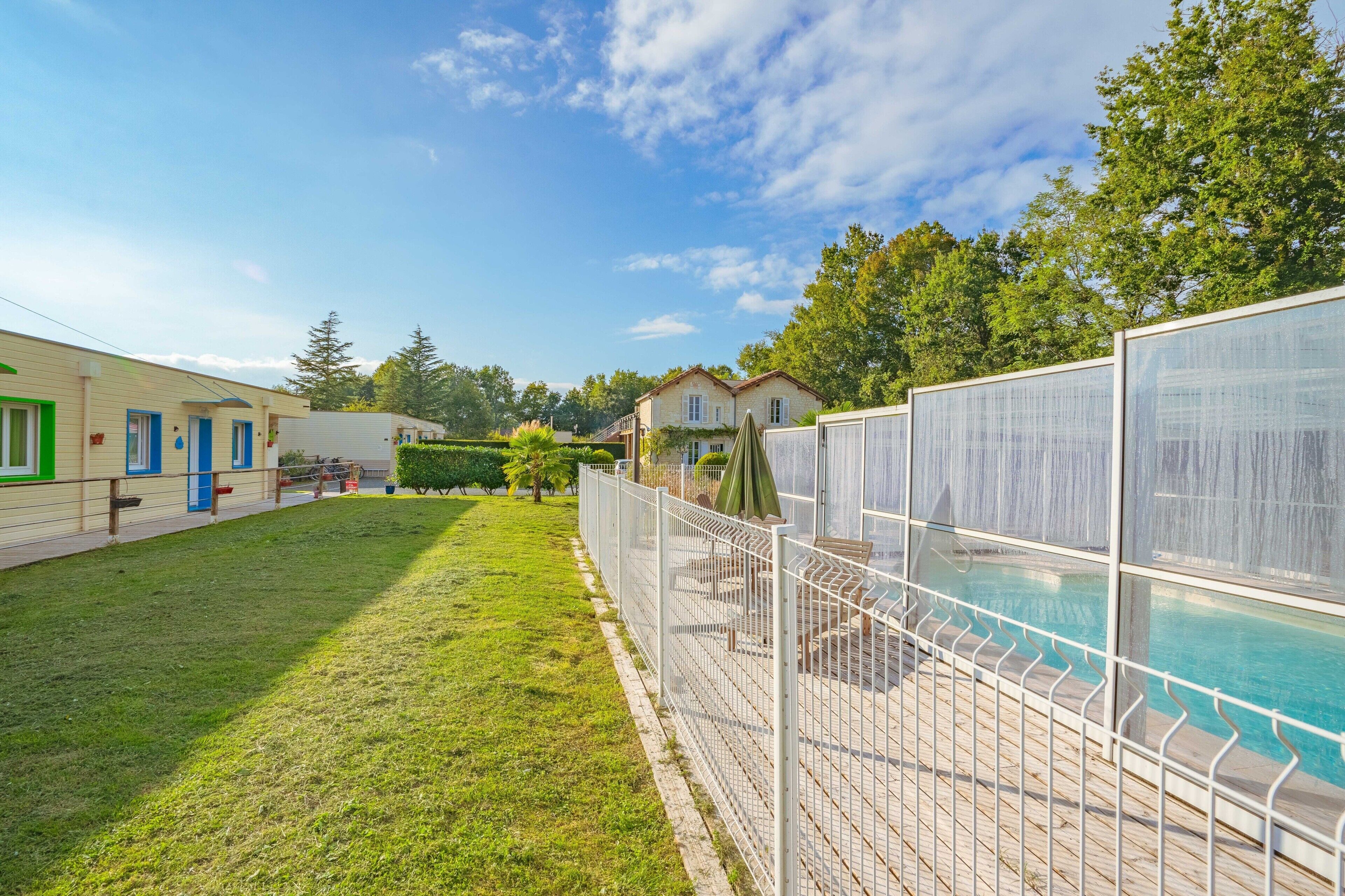 A residential area with a swimming pool, a fenced patio, and a house with a balcony.