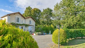 A stone building with a gravel driveway, surrounded by lush greenery and a well-maintained garden. - Apartment 'Le Clos Du Champ De L'Amour - Royan' with Private Pool, Wi-Fi & Air Conditioning (Saint-Simon-de-Bordes)