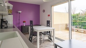 A modern kitchen with a white countertop, a purple wall, and a dining area with a white table and chairs. - Apartment 'Le Clos Du Champ De L'Amour - Talmont' with Private Pool, Wi-Fi & AC (Saint-Simon-de-Bordes)
