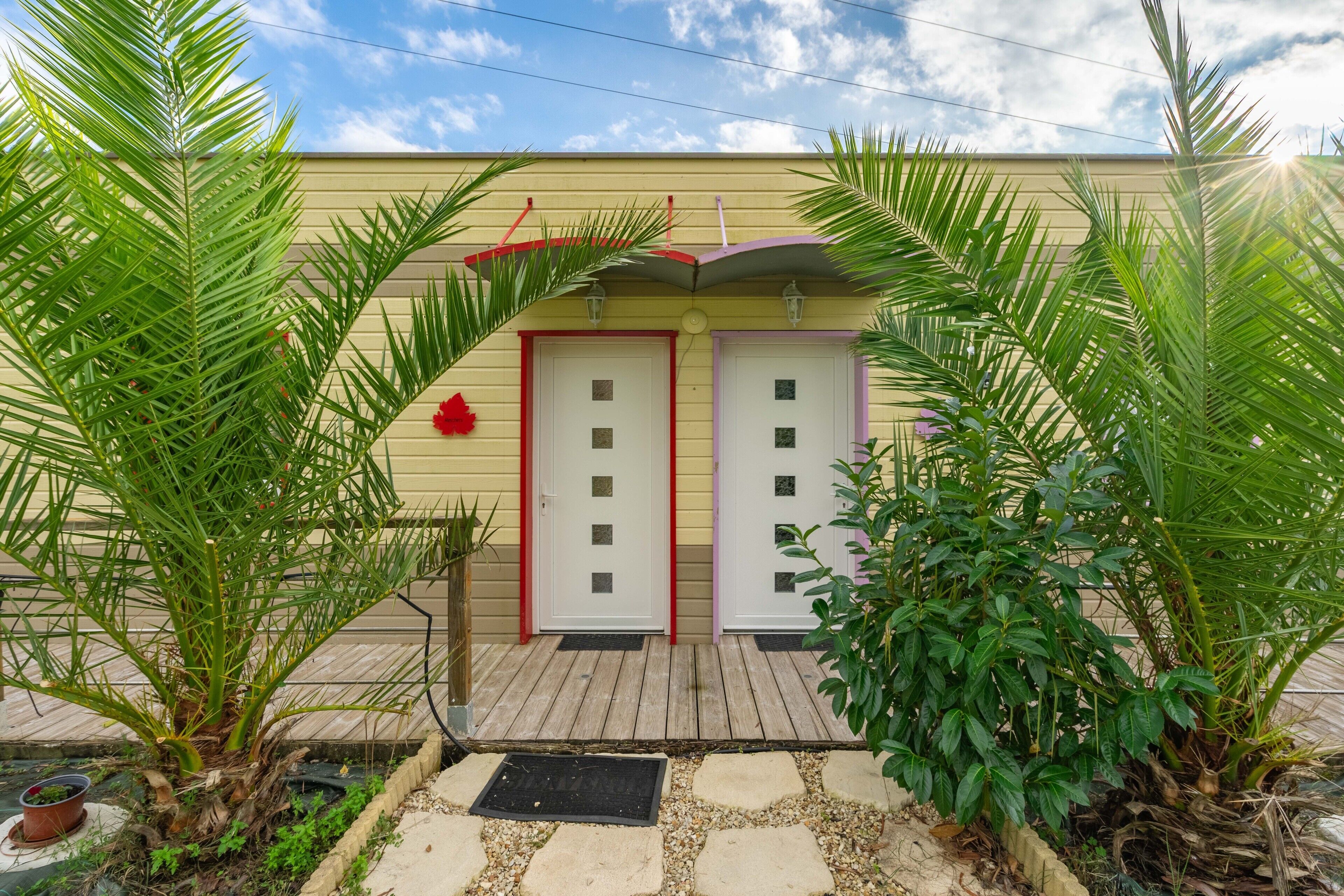 A building with two doors, a wooden deck, and surrounding greenery.