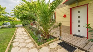 Ein Haus mit roter Tür, einem Kiesweg und einer Palme.