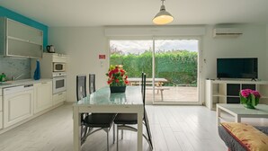 Cozinha moderna com área de jantar, televisão e vista para o verde.