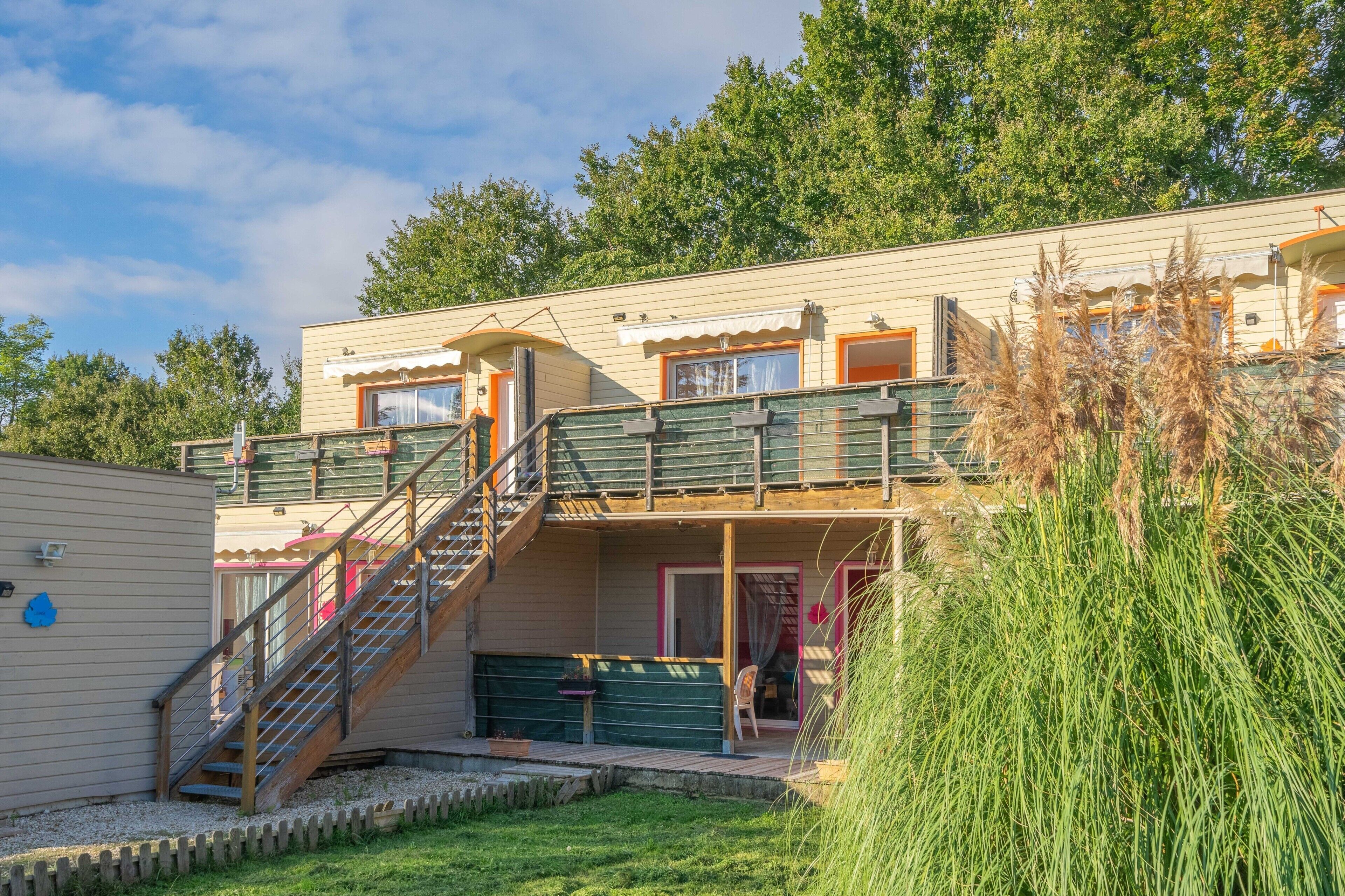 Ein zweistöckiges Gebäude mit Balkon, Treppe und überdachtem Außenbereich.