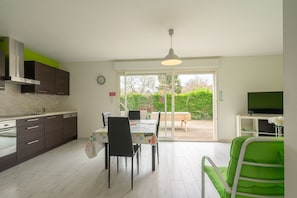 A modern kitchen with a dining area, a TV, and a sliding glass door leading to an outdoor patio.