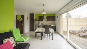 Eine moderne Küche mit Essbereich, einem Sofa und einem grünen Sessel, sowie einem großen Fenster.