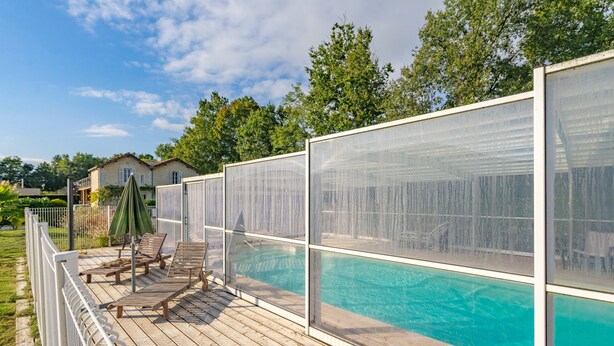 Ein Poolbereich mit Holzterrasse, Liegestühlen und Sichtschutz.