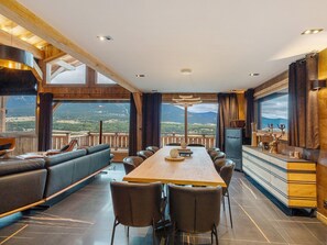 A spacious dining area with a long table, leather seating, and a view of mountains.