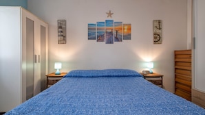 Una camera da letto con un letto, due comodini con lampade, un armadio e opere d'arte alle pareti.