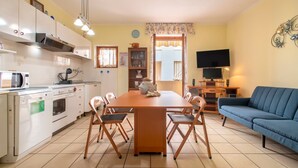 Un ambiente compatto con angolo cottura, zona pranzo e divano.