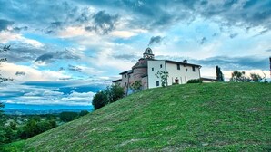 A building with a bell tower, situated on a grassy hill with a cloudy sky. - Apartment 'Holiday Home In Tuscany' with Mountain View, Private Terrace and Wi-Fi (Castelfiorentino)
